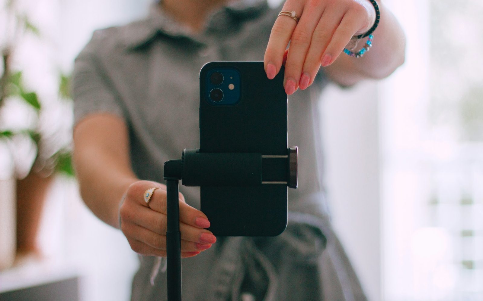 Eine Person richtet ein Smartphone auf einem Stativ aus, im Hintergrund ein heller Raum